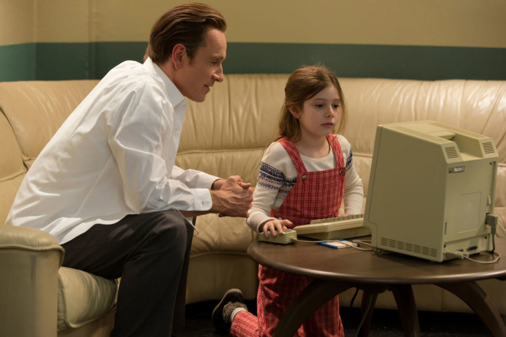 In this image released by Universal Pictures, Michael Fassbender, left, as Steve Jobs and Makenzie Moss as a young Lisa Jobs, appear in a scene from the film, "Steve Jobs." The movie releases in the U.S. on Friday, Oct. 9, 2015. (Francois Duhamel/Universal Pictures via AP)