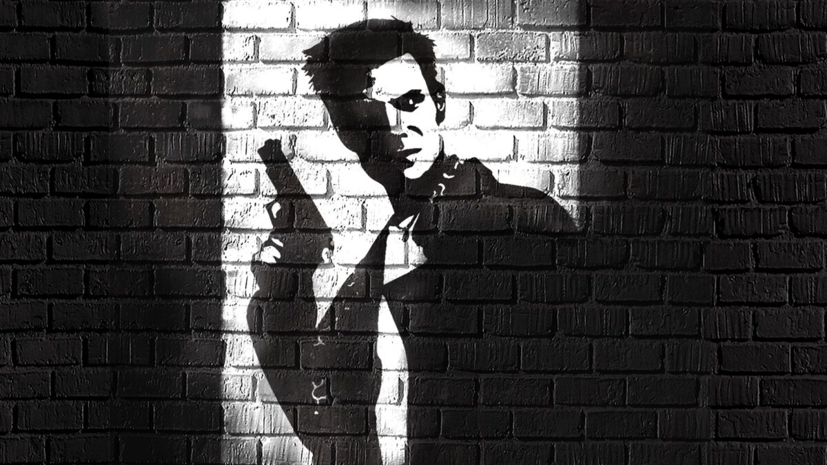 Max Payne tuğla duvar önünde, elinde tabancayla