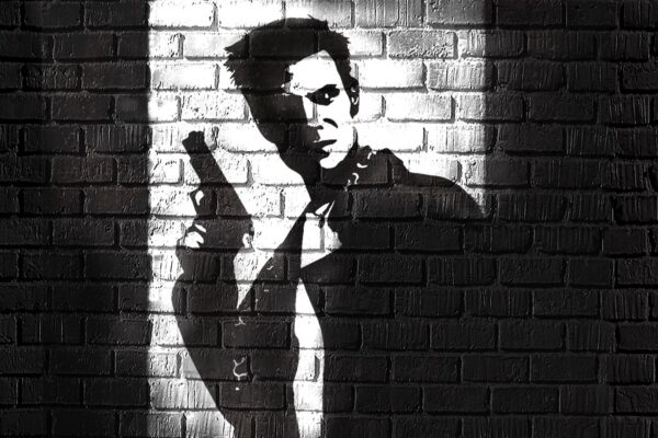 Max Payne tuğla duvar önünde, elinde tabancayla